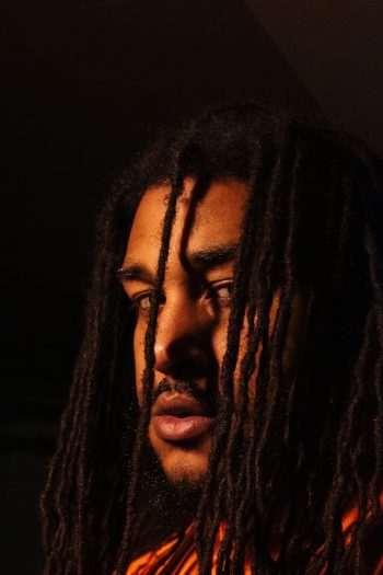 headshot of Tyreek Phillips, dark background, organte-yellow lighting, profile from the side