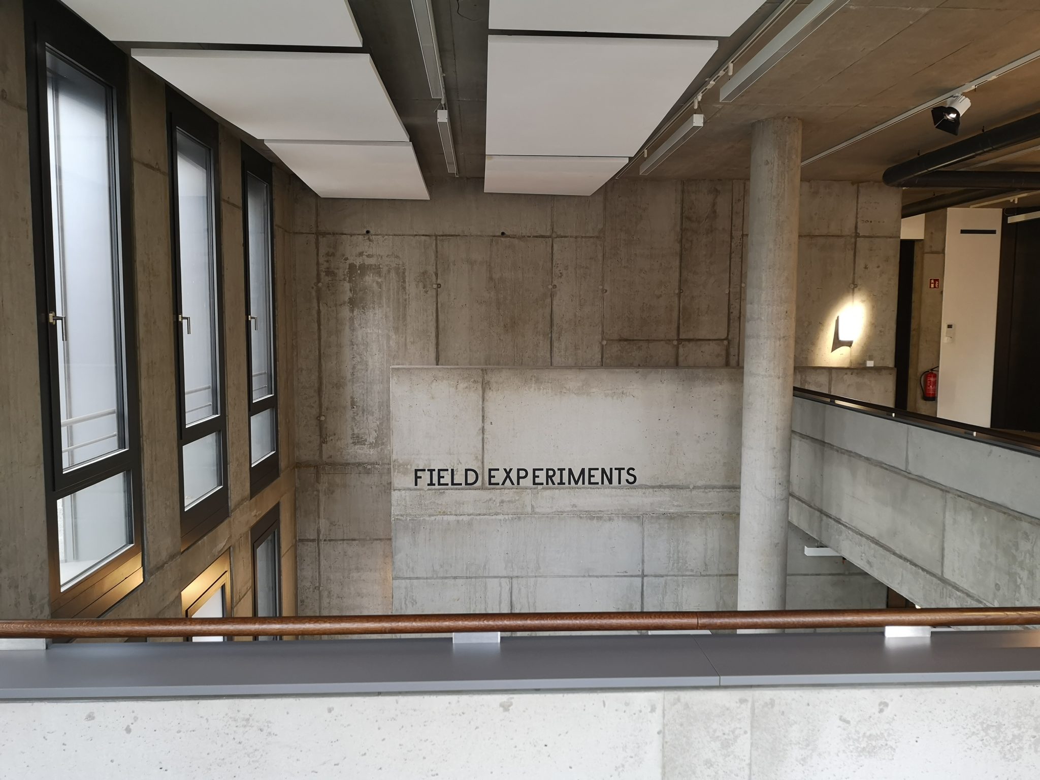 inside photo of STATE Studio (now closed) in Berlin. The walls and pillars are unadorned concrete and the label Field Experiments is the only adornment on the south-facing wall